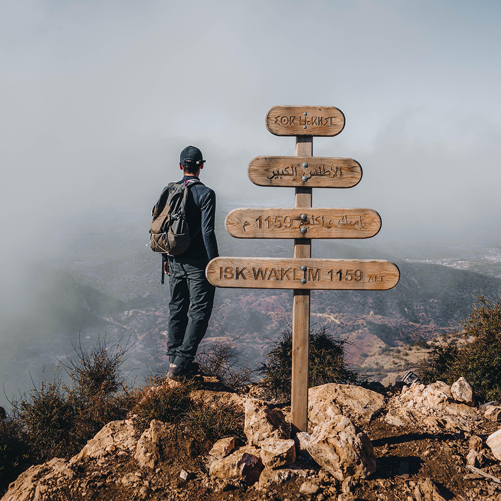 Young man standing on a mountain peak called ISK WAKLIM 1159 in Morocco